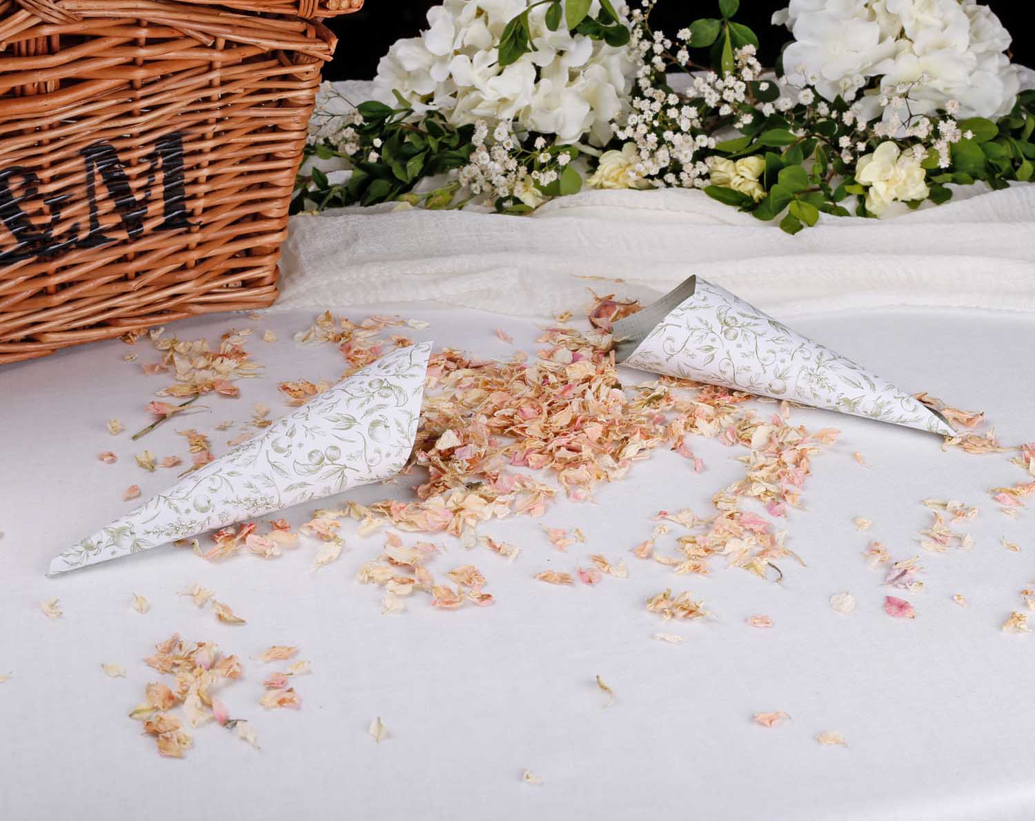 Sage Garden Wedding Confetti Cones surrounded by flower petals next to a wicker basket, ideal for wedding ceremonies.