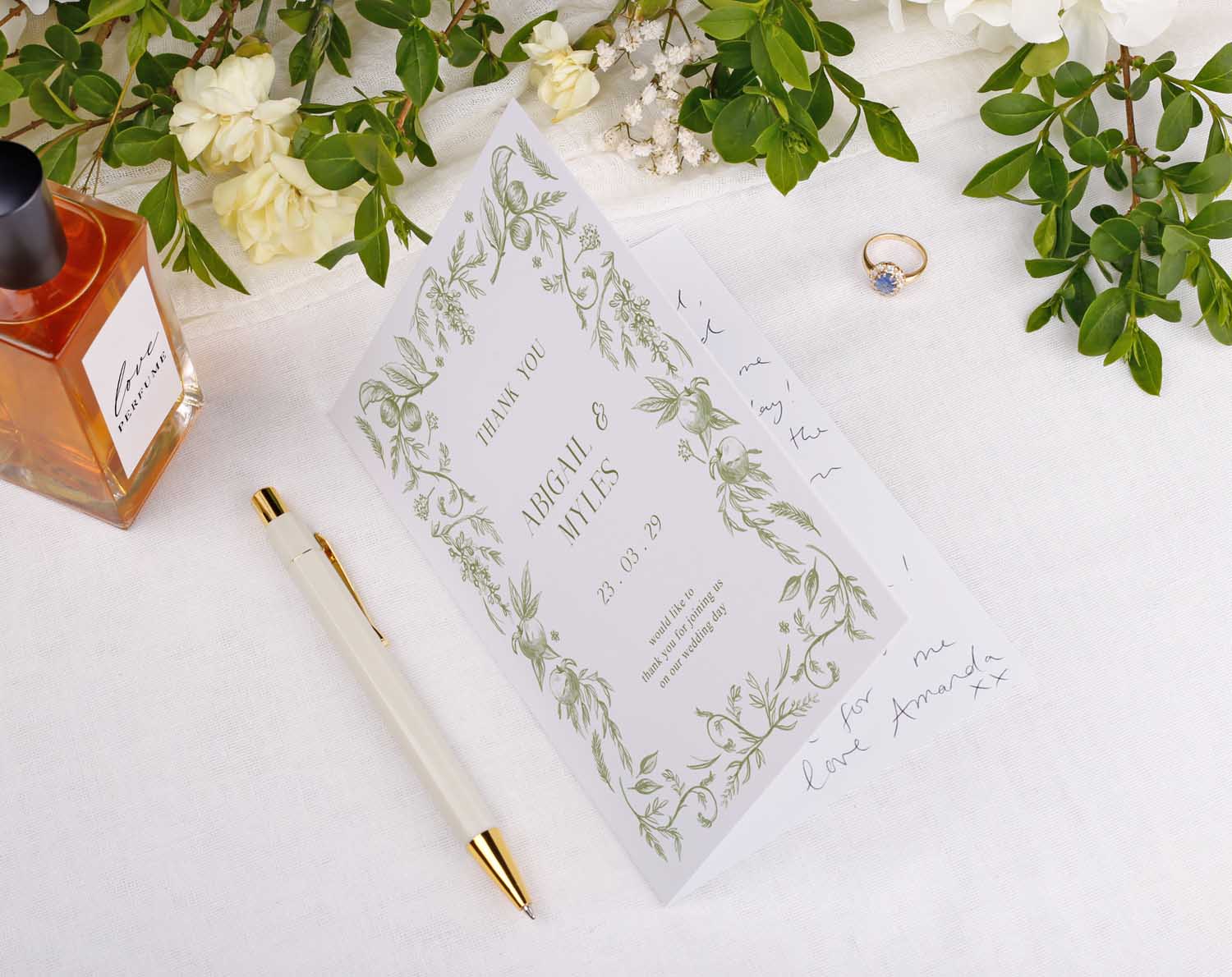 Image of Sage Garden Wedding Thank You Cards on a white table with a perfume bottle, ring, and pen.