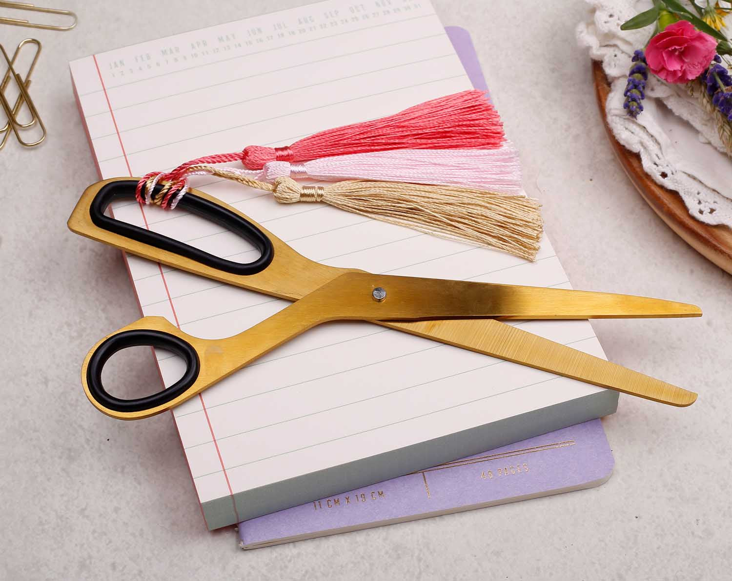 pair of gold scissors with tassels and black rubber handle details
