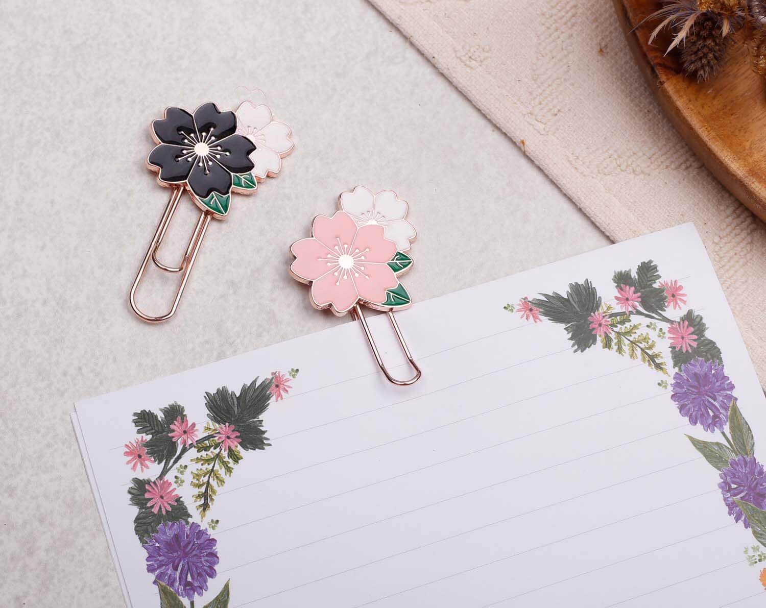 Set Of Flower Paper Clips featuring black and pink enamel floral designs on metal clips, perfect for organizing notes.