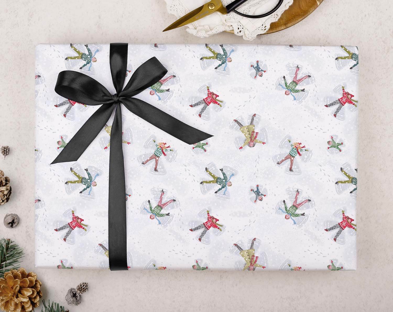 Snow Angels Christmas Wrapping Paper with colorful snow angel designs and a black ribbon for holiday gift wrapping.