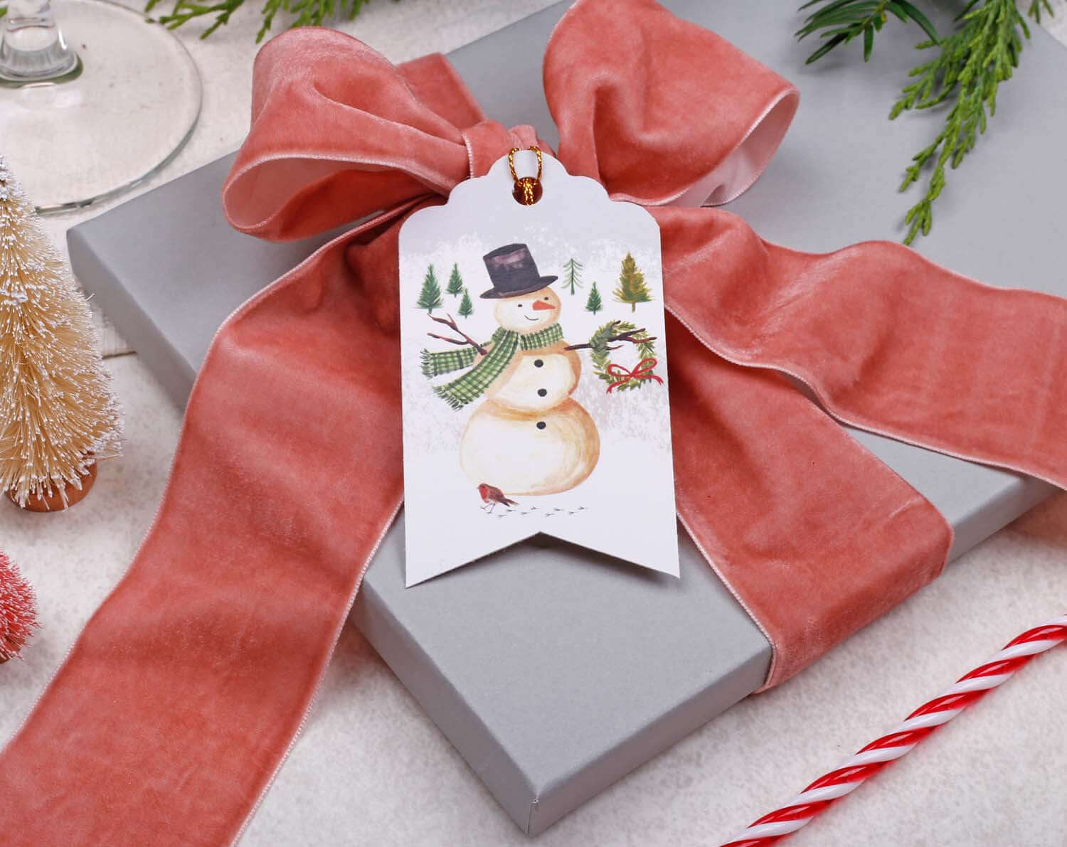 Snowman Christmas Gift Tags attached to a gift with a pink bow, featuring a cheerful snowman design.