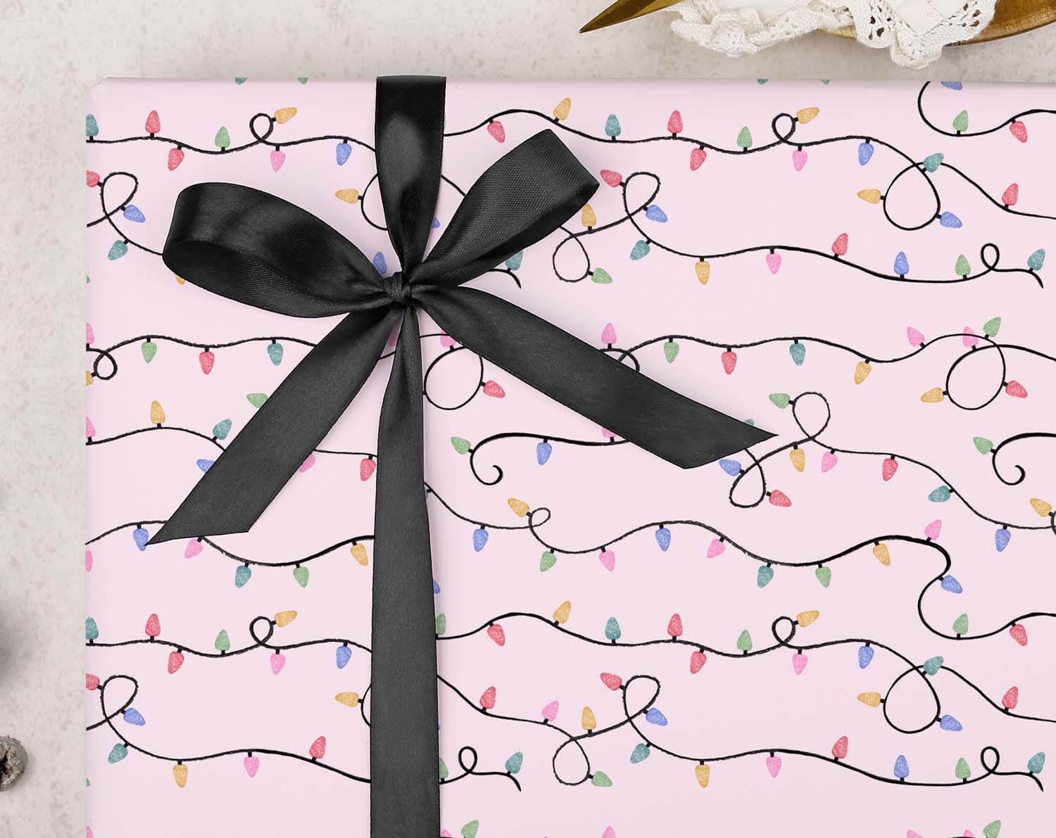 Vintage Christmas Lights Wrapping Paper with black ribbon on pink background featuring colorful lights.