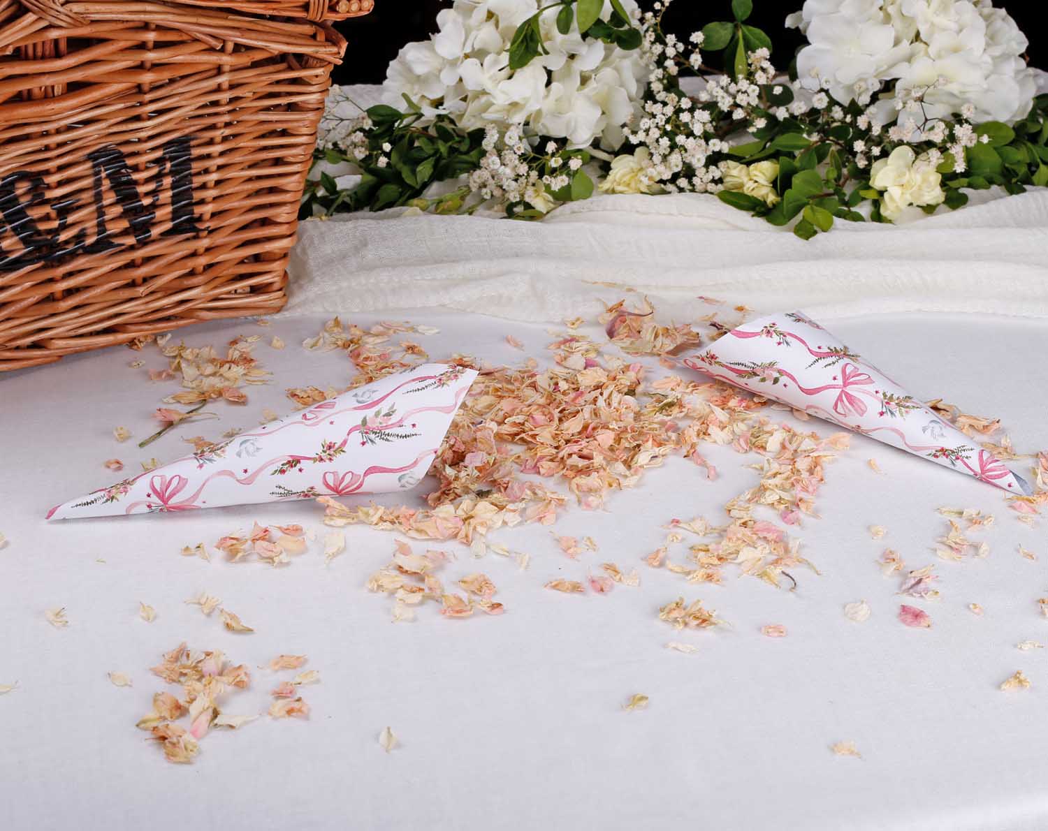 Vintage Wedding Confetti Cones scattered on a table with dried petals beside a wicker basket.