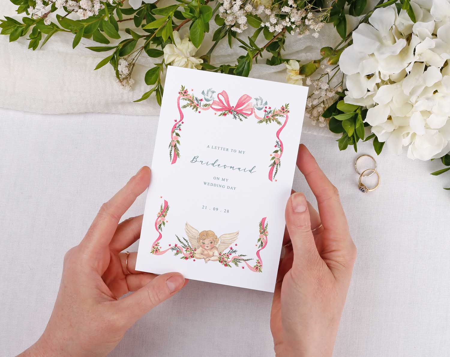 Vintage Wedding Thank You Card design held in hands with floral decorations and an angel illustration.