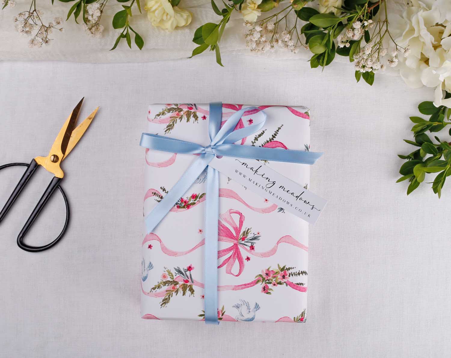 Beautifully wrapped gift featuring Vintage Wedding Wrapping Paper with floral design and blue ribbon, perfect for weddings.