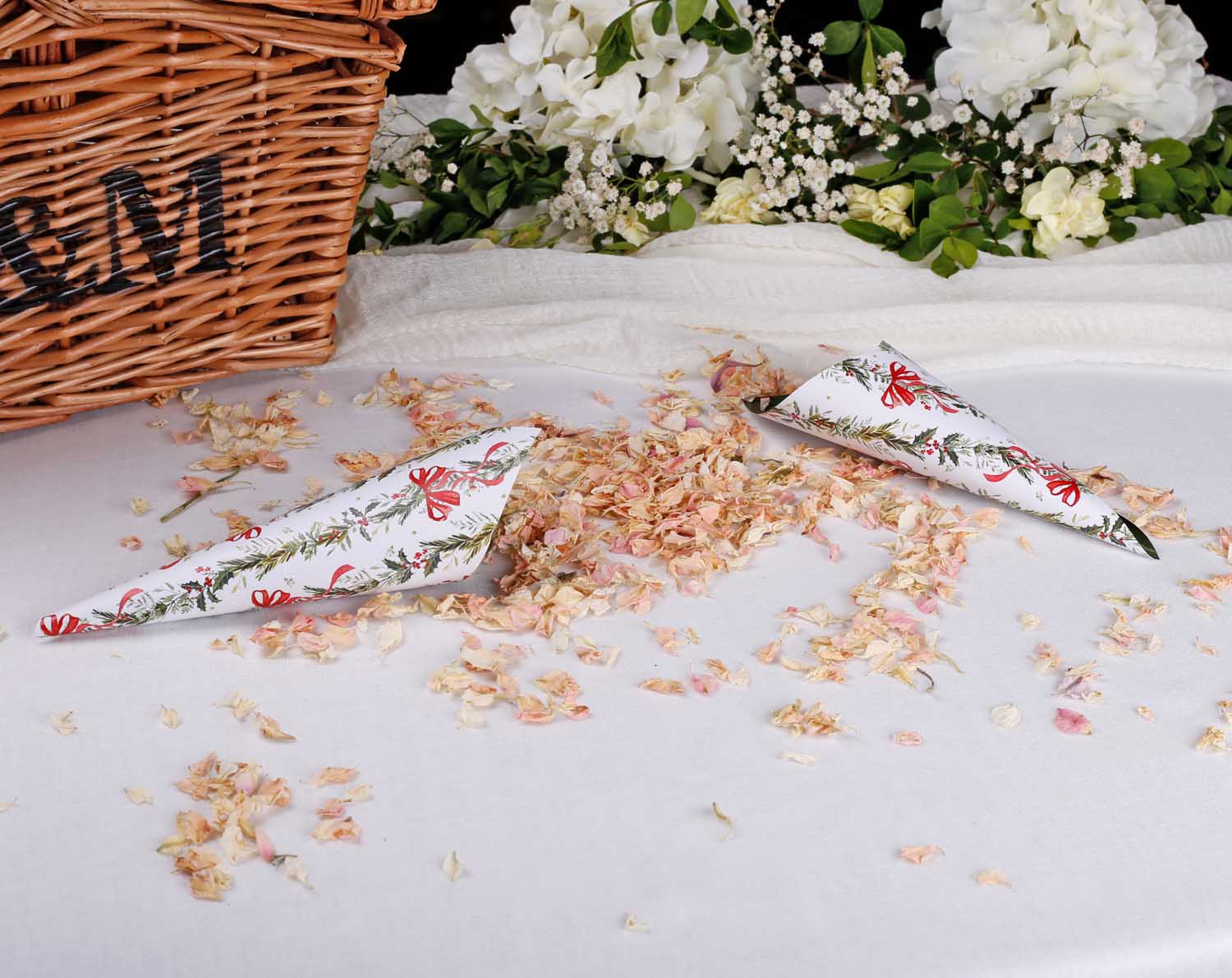 Winter Wedding Confetti Cones displayed on a table with floral confetti and a wicker basket in the background.