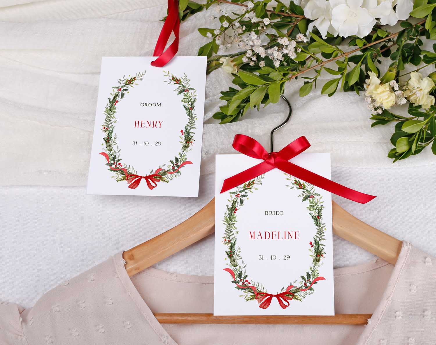 Winter Wedding Hanger Tags displayed on a hanger with floral designs and red ribbons for groom and bride.