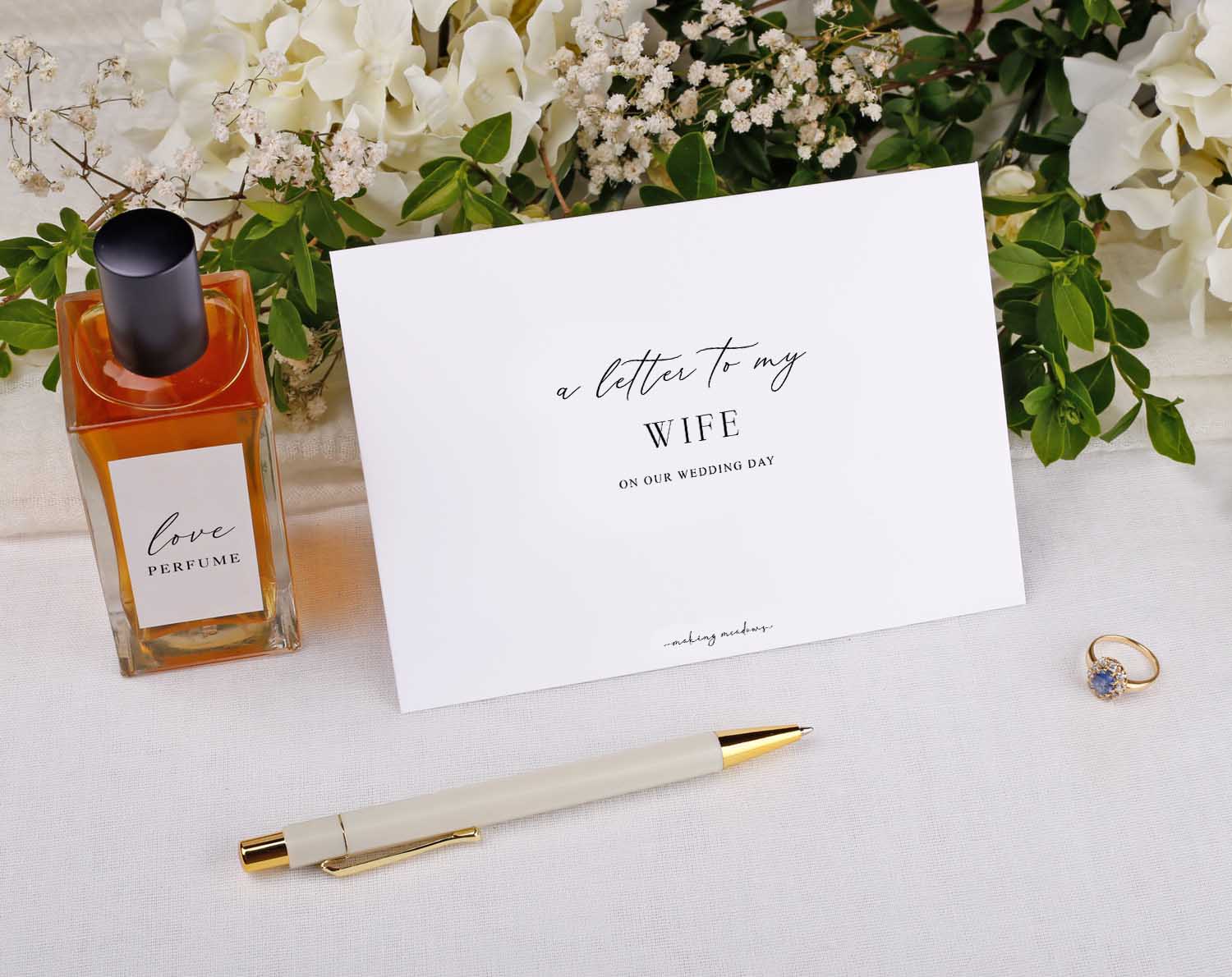 Winter Wedding Letter to My Wife kit with perfume, pen, and beautiful card on a table decorated with foliage.