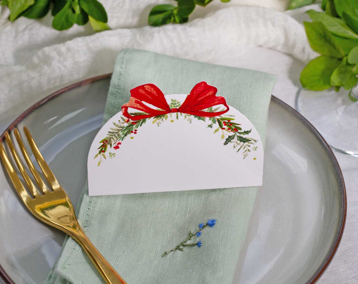 Colorful Winter Wedding Place Cards with red ribbon on a green napkin at a beautifully set dining table.