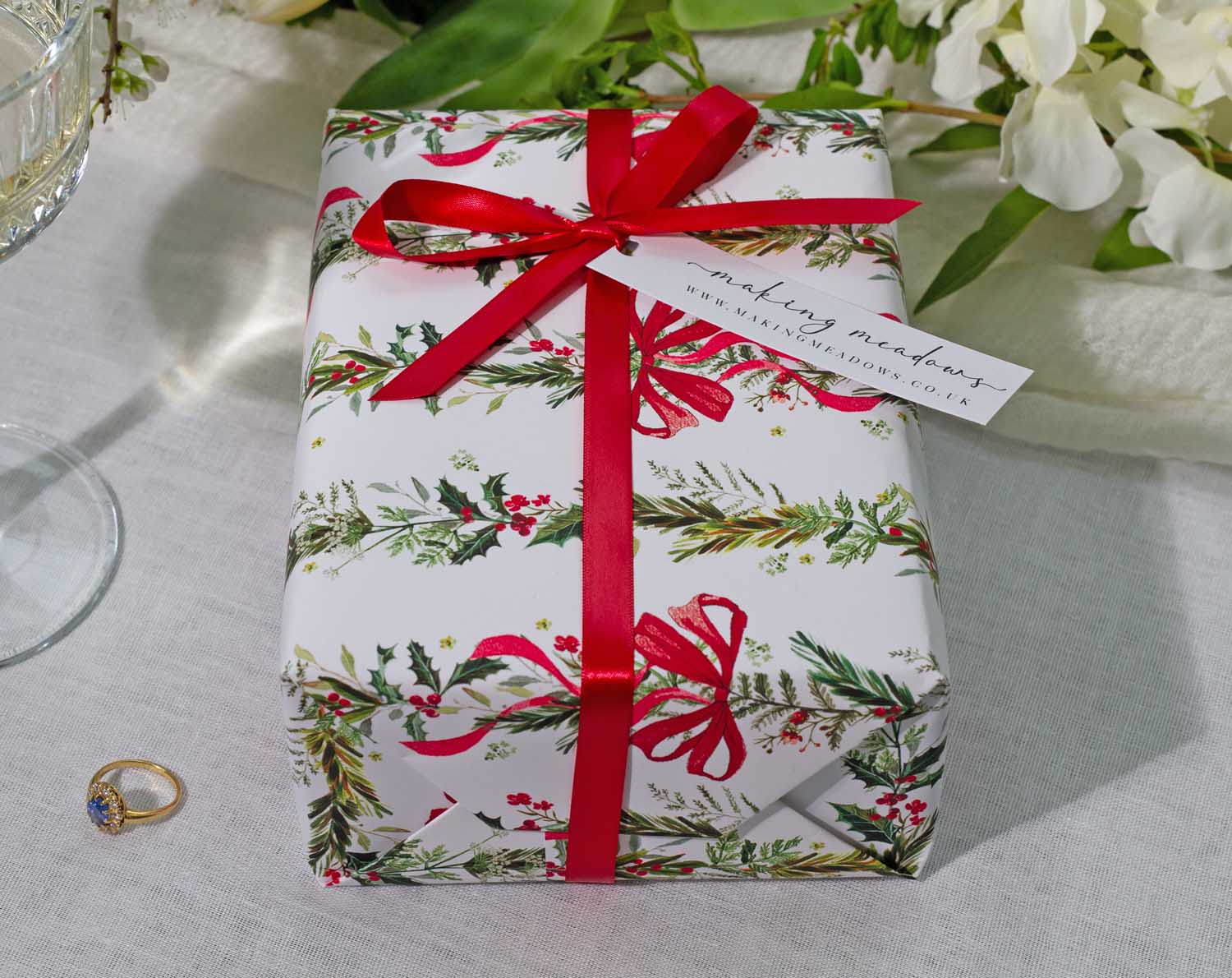 A beautifully wrapped gift in Winter Wedding Wrapping Paper with red ribbon and tag, perfect for wedding celebrations.