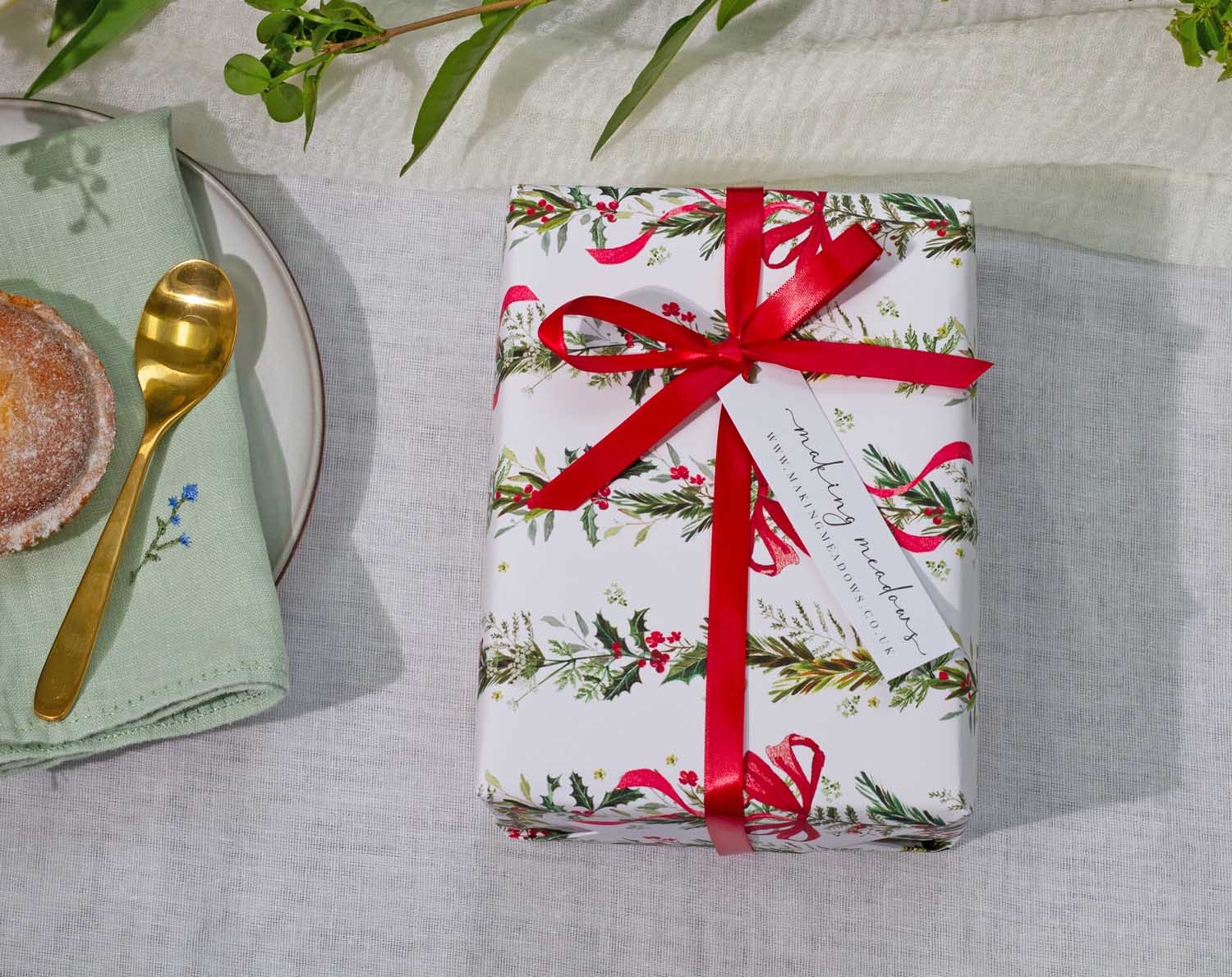 Winter Wedding Wrapping Paper beautifully wrapped gift with festive ribbon on a table with a plate and spoon.