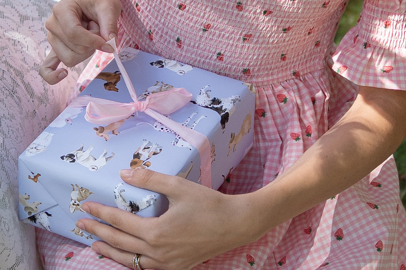 young girl unwrapping a present with dog wrapping paper on