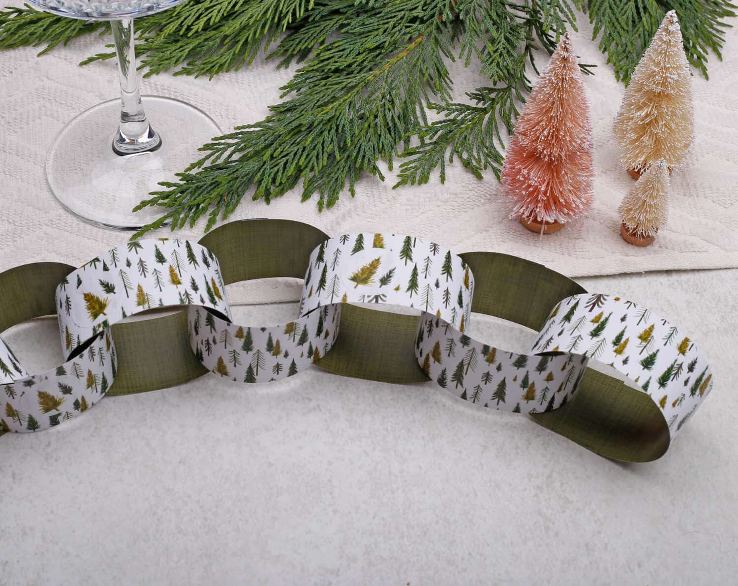 Forest Christmas Paper Chains Garland with festive designs, interlinked and displayed with decorative trees.