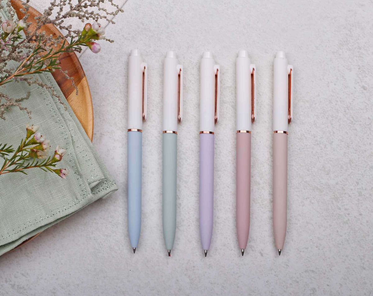 Lilac Gel Pen with rose gold trim among pastel-colored pens on a textured surface, showcasing stylish writing tools.