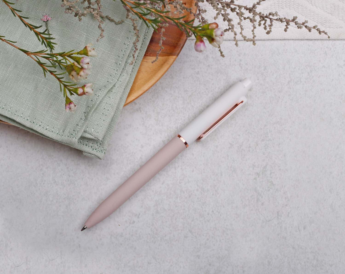 Apricot Gel Pen with Rose Gold Trim on a light grey background next to a green napkin and flowers.