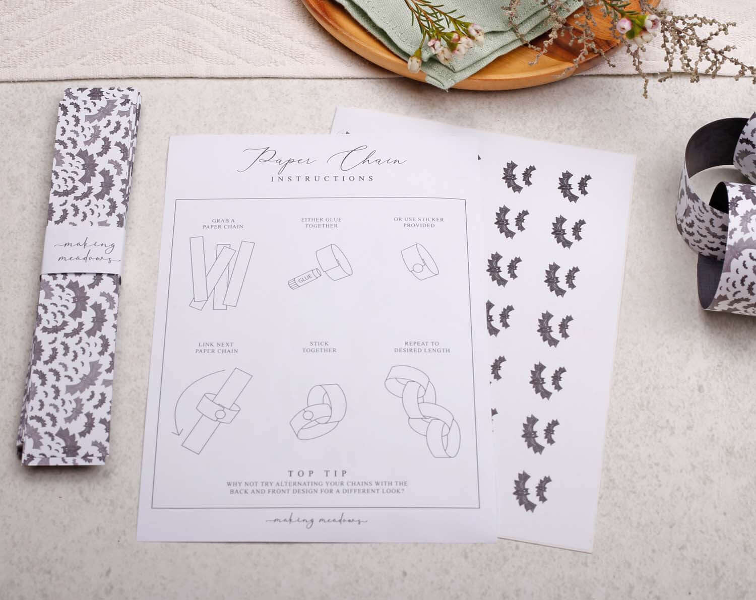 Bat Halloween Paper Chains instructions sheet with decorative bat designs and assembly tips on a tabletop.
