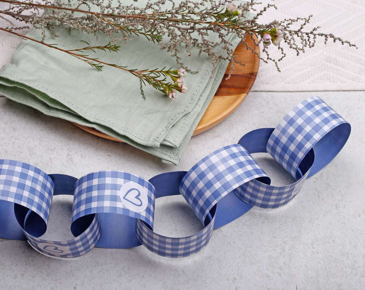 Blue Gingham Paper Chains displayed on a table with green napkins and decorative flowers.