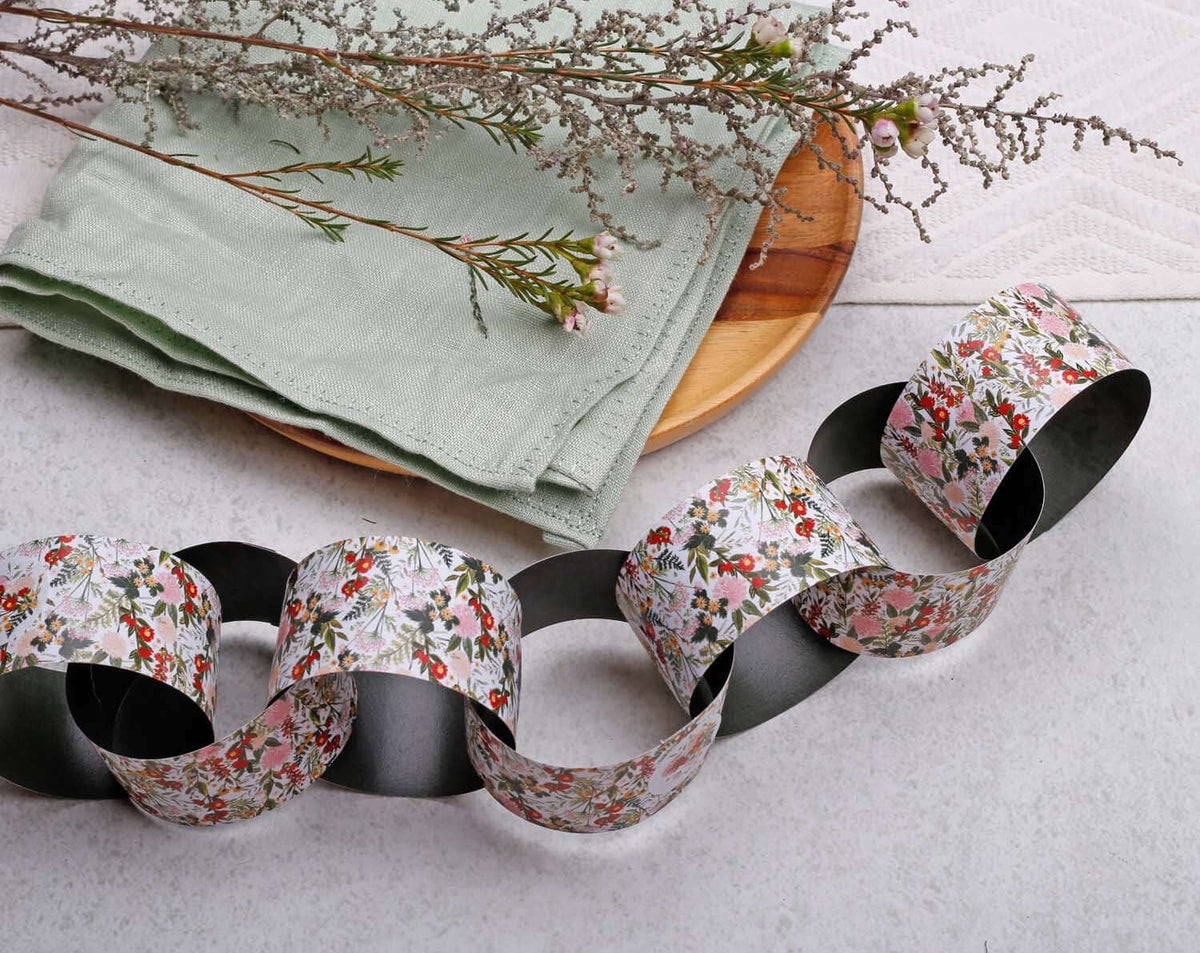 Boho Floral Paper Chains garland displayed on a table with green napkin and wooden plate.
