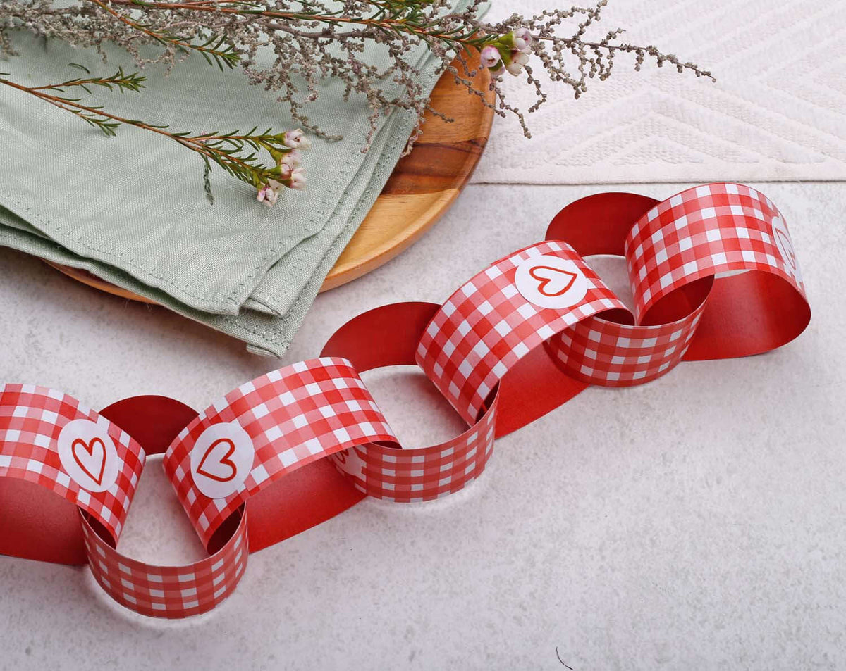 Red Gingham Paper Chains decoration laid out with green napkins and flowers, perfect for festive occasions.