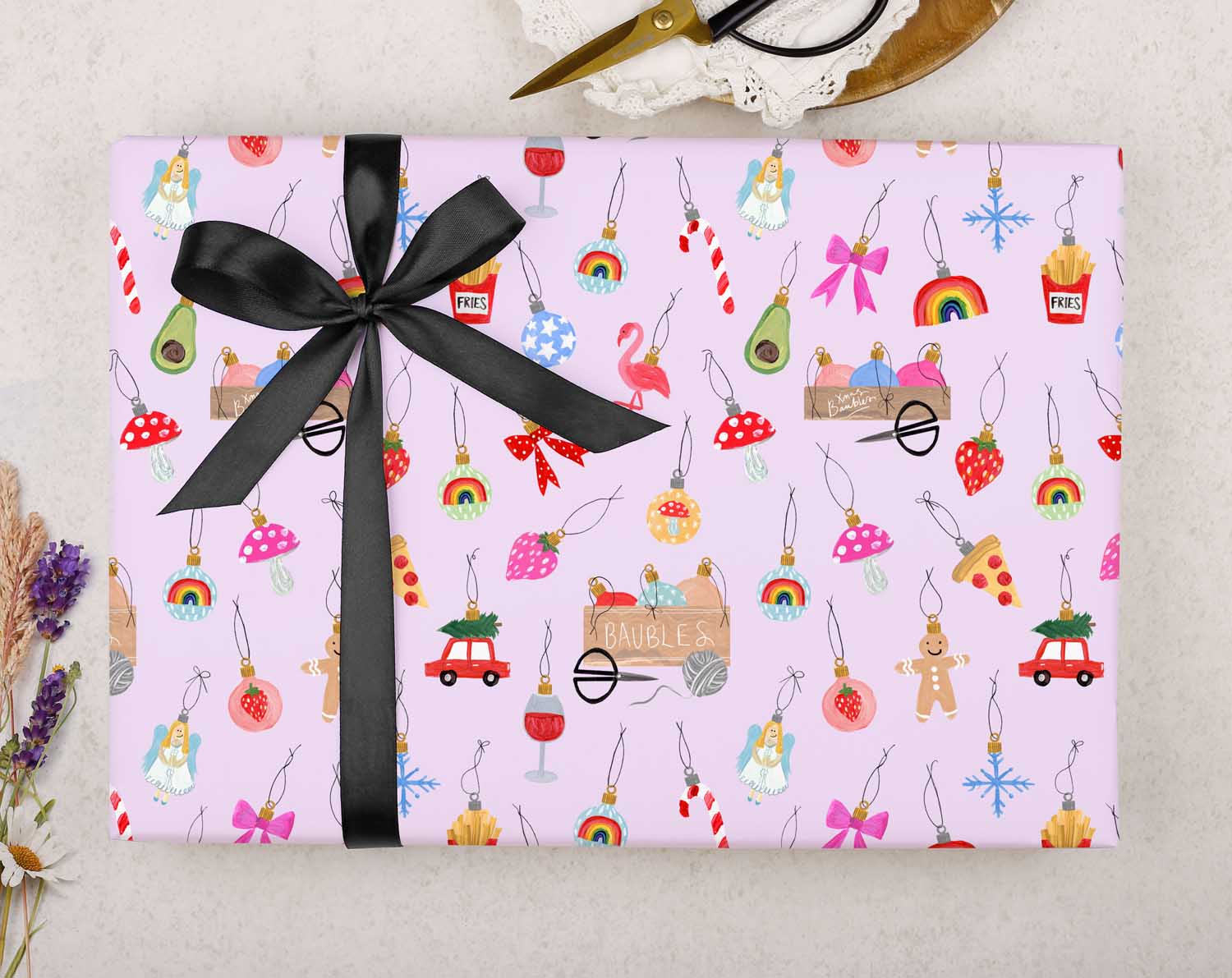 festive Christmas wrapping paper is filled with Christmas Ornaments on a lilac background