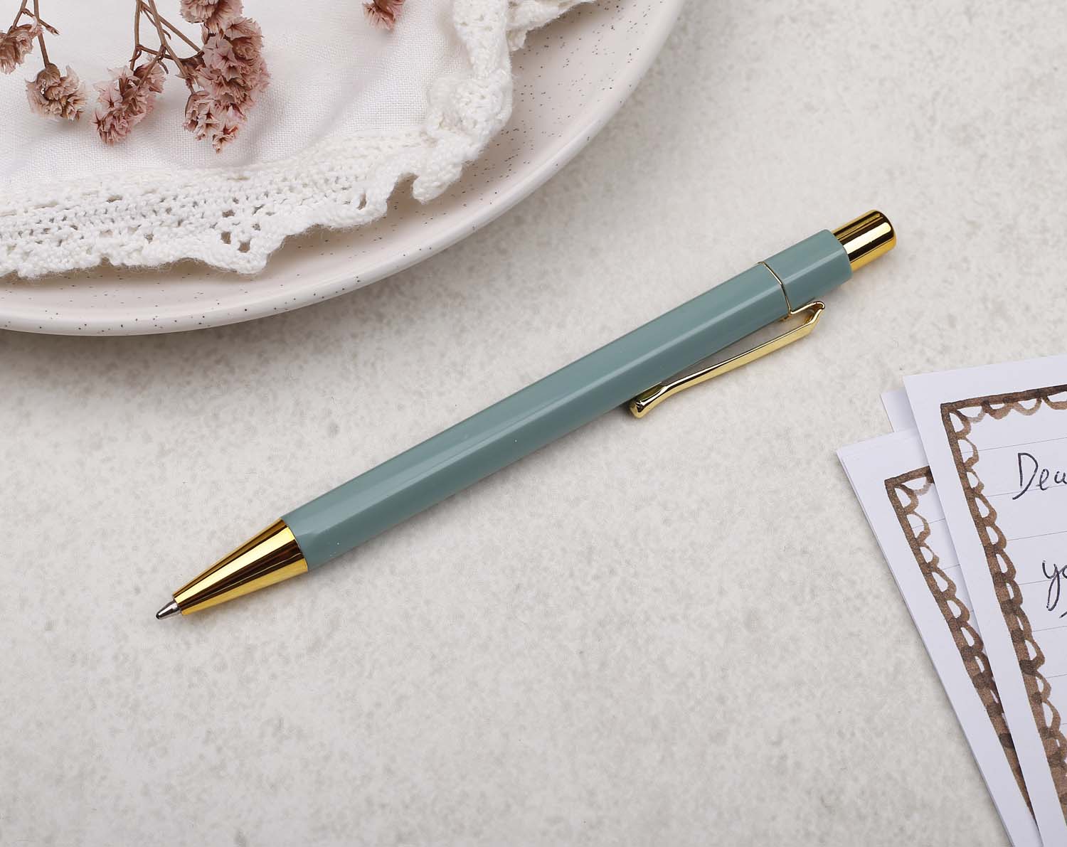 A premium sage green and gold pen with ballpoint tip and hexagonal barrel detail. 