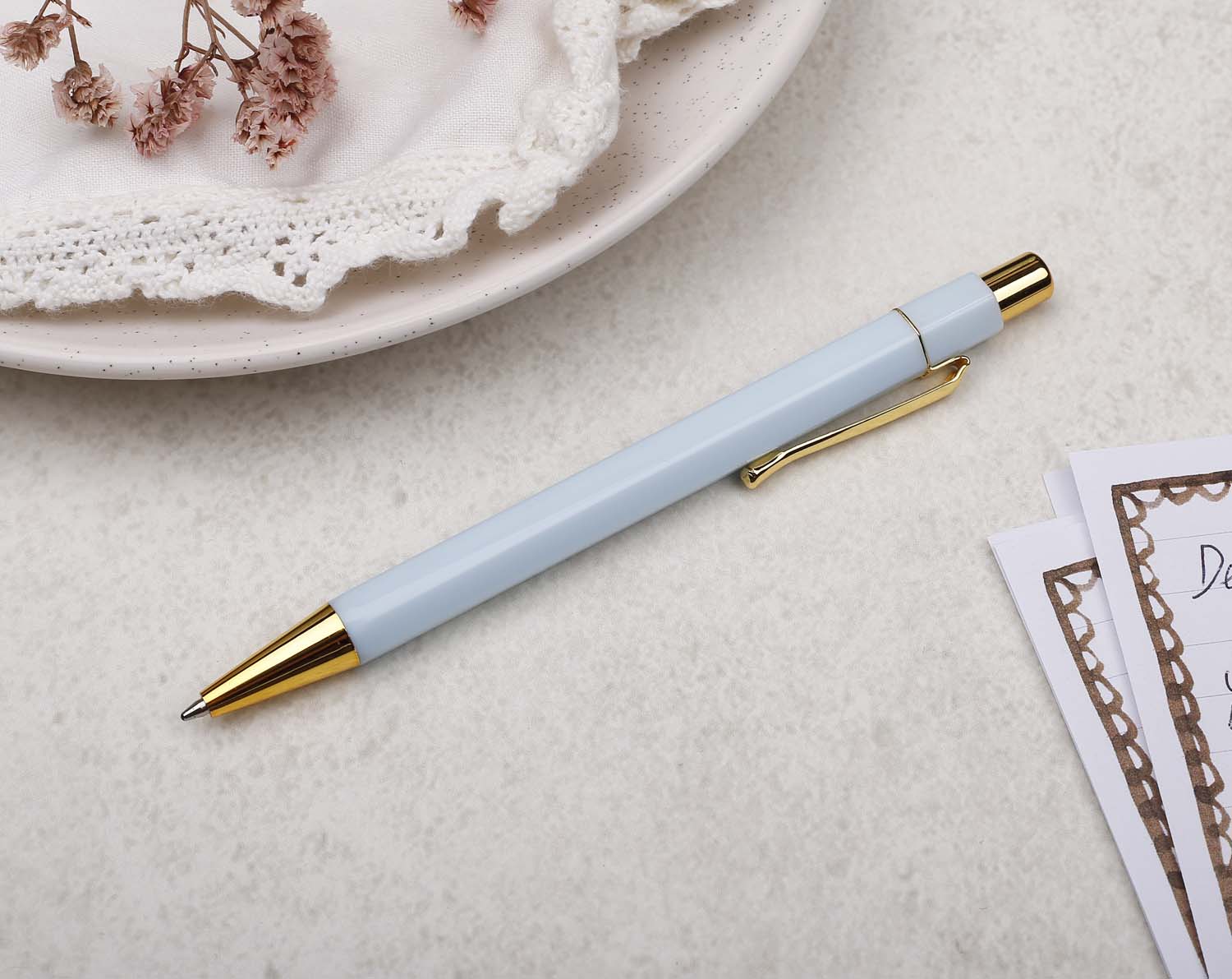 A premium light blue and gold pen with ballpoint tip and hexagonal barrel detail.