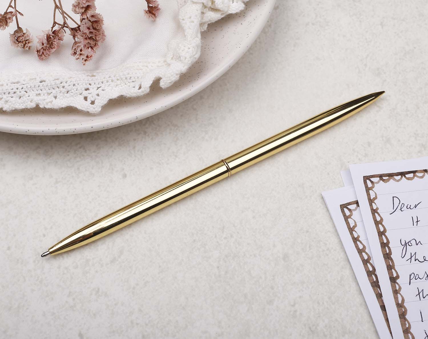 Slim gold metal pen with ballpoint tip and gold detail.