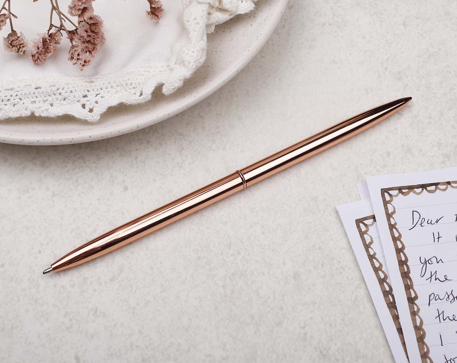 Slim rose gold metal pen with ballpoint tip and rose gold detail. 
