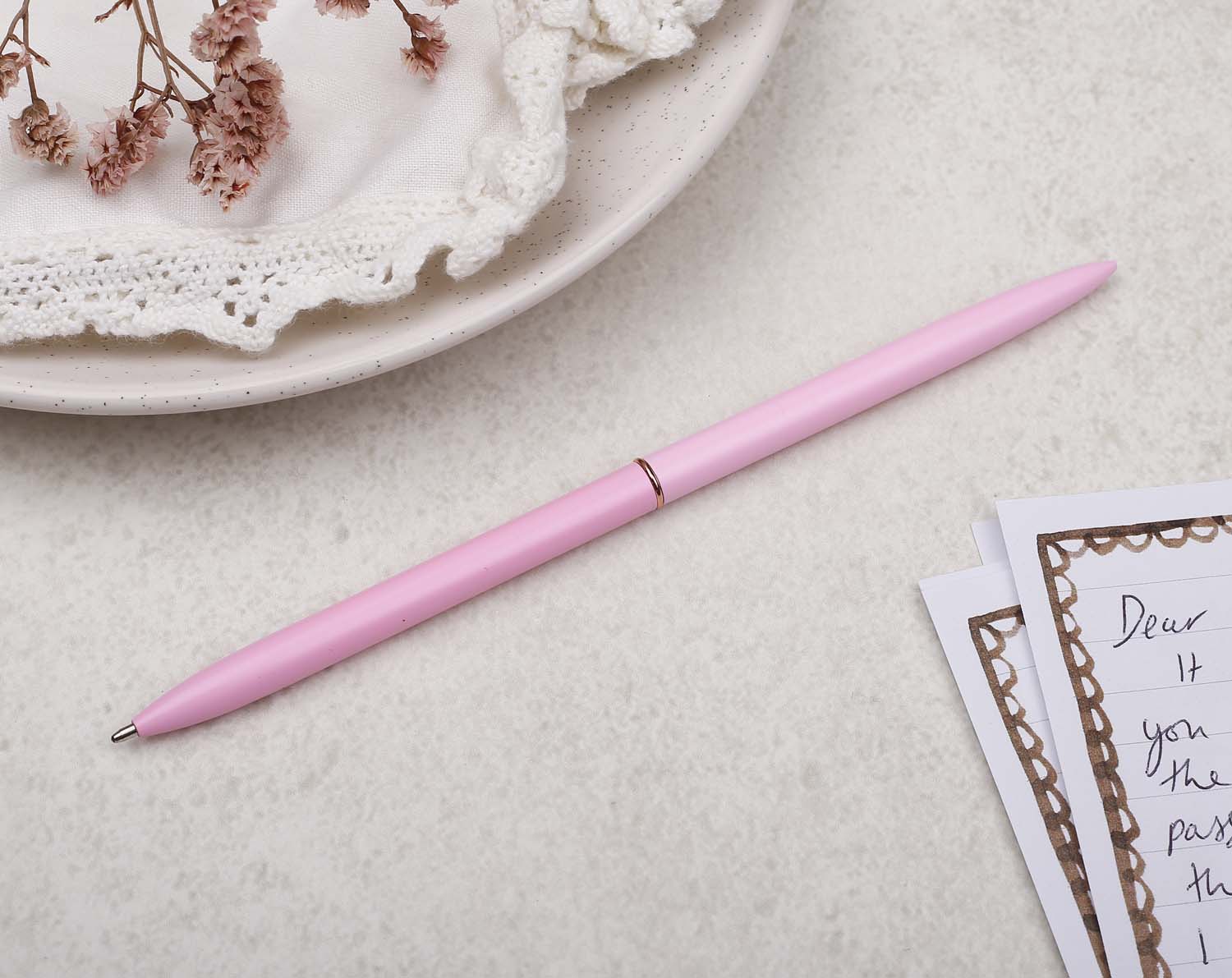 Slim pink metal pen with ballpoint tip and rose gold detail.