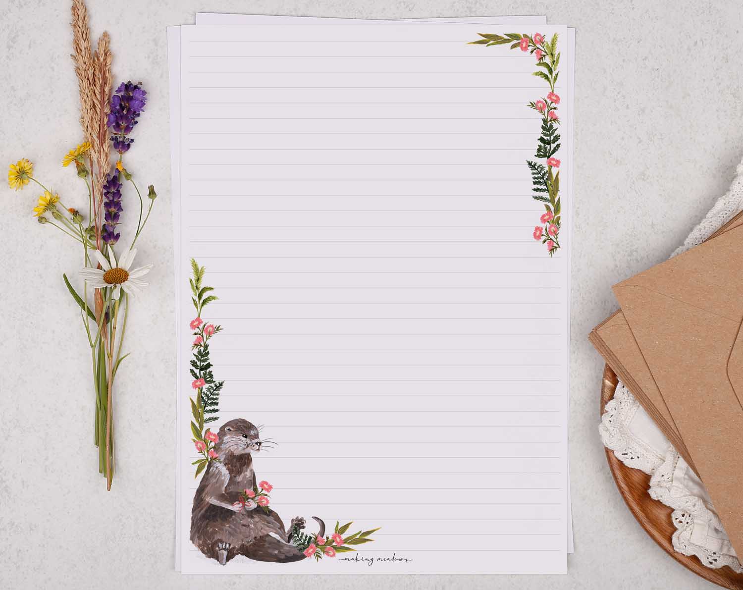 A4 letter writing paper sheets with a cute sitting otter and a delicate pink floral watercolour border cascading around the letter paper edge.