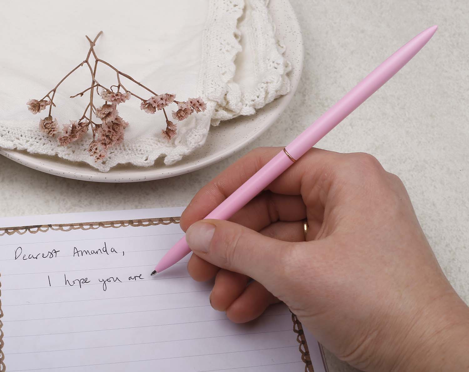 Slim pink metal pen with ballpoint tip and rose gold detail.