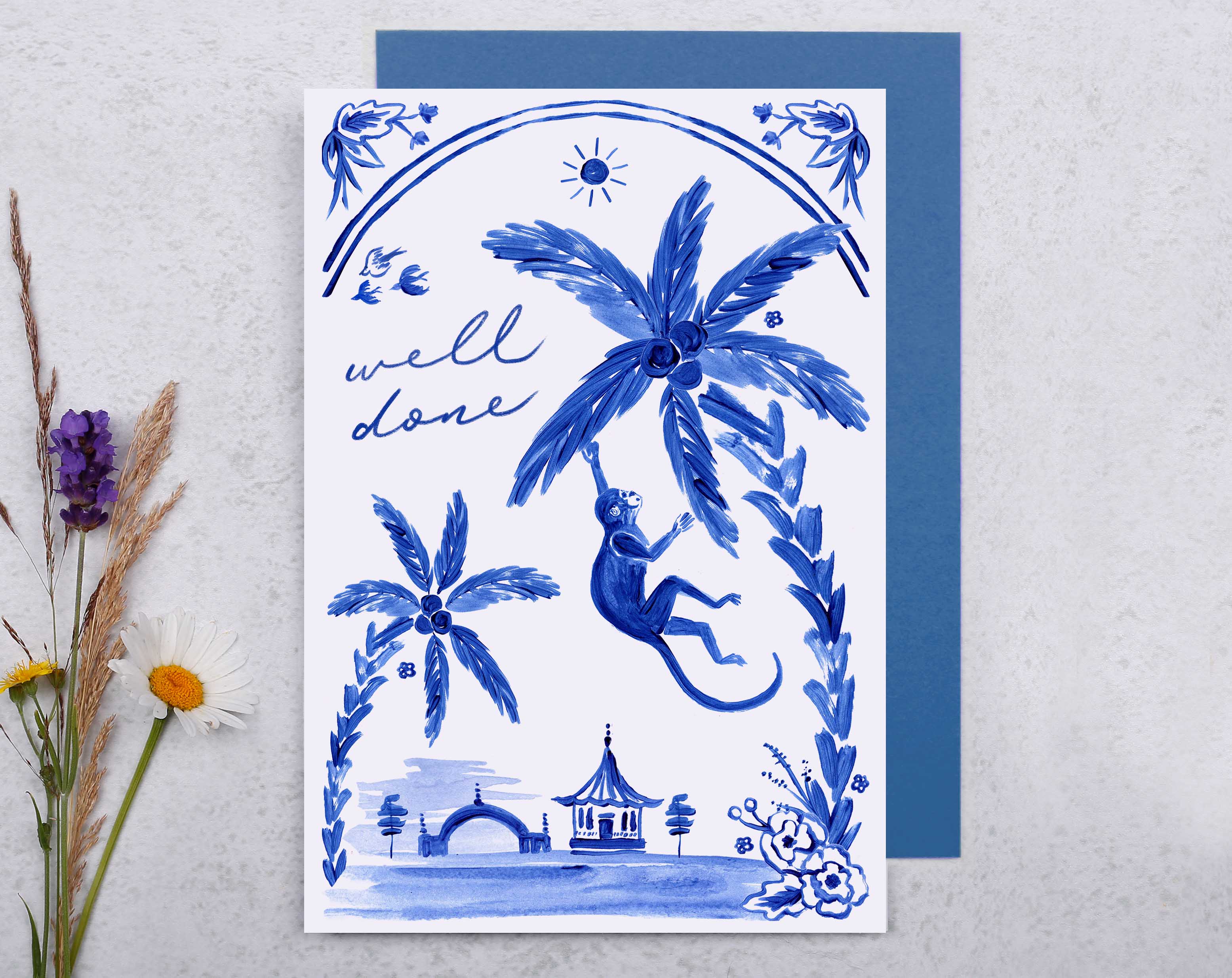 A blue porcelain inspired Well Done Card with a joyful monkey swinging from a palm tree. 