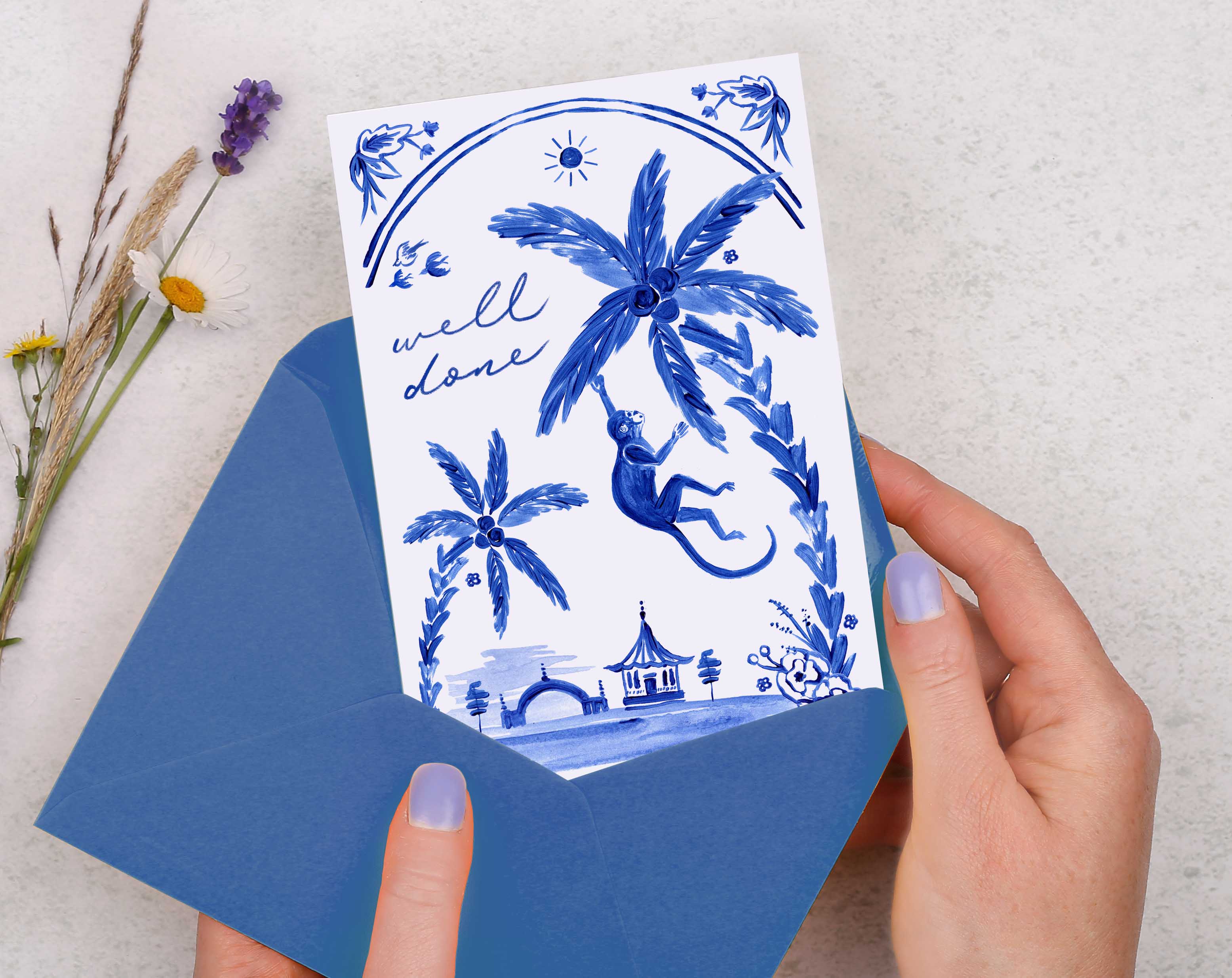 A blue porcelain inspired Well Done Card with a joyful monkey swinging from a palm tree. 